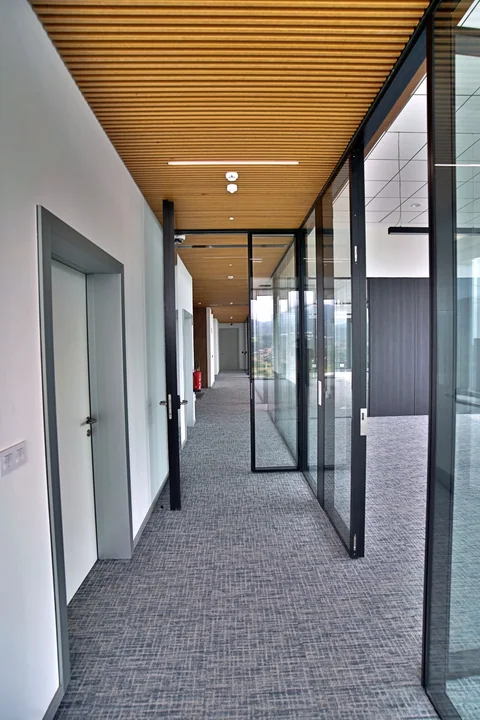 Paneles acústicos decorativos Woodslines: techo de lamas de madera en un pasillo de oficinas de Bilbao, ejemplo de revestimiento cuyo mantenimiento necesita acceso planificado.